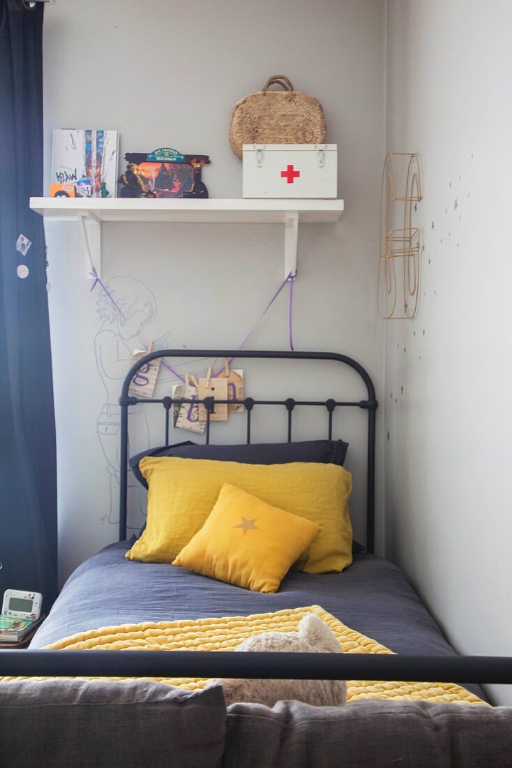 Metallbett mit grauer und gelber Bettwäsche im Kinderzimmer