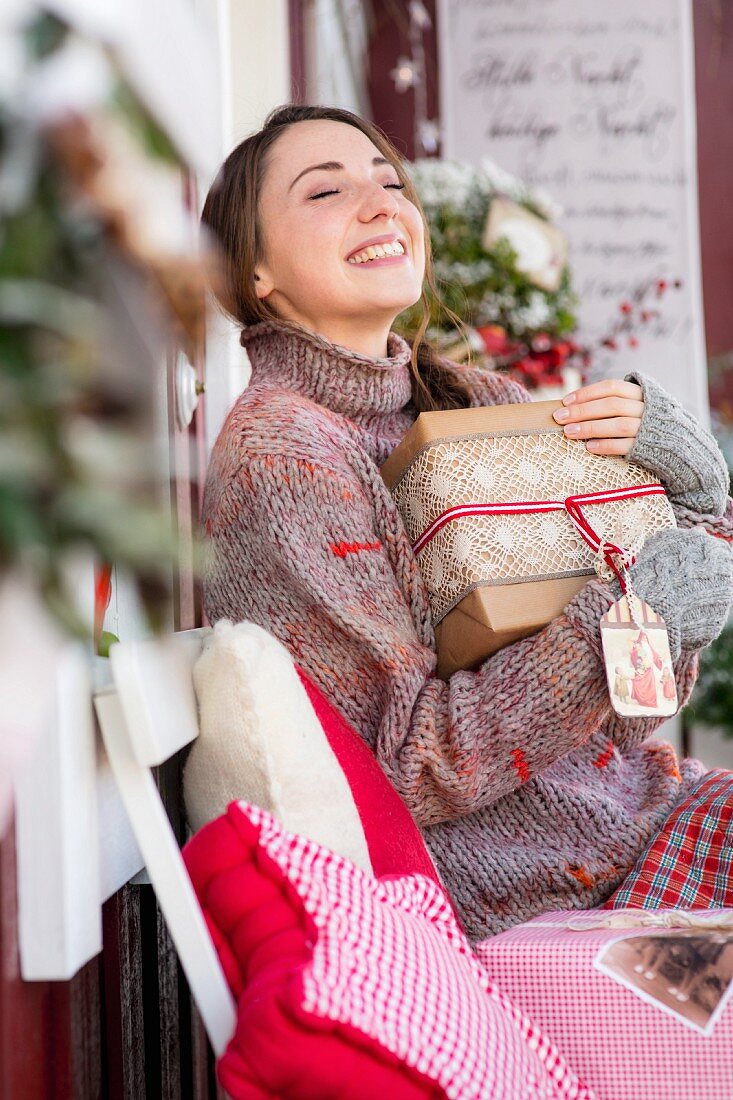 Junge Frau freut sich über Geschenke auf dekorierter Veranda