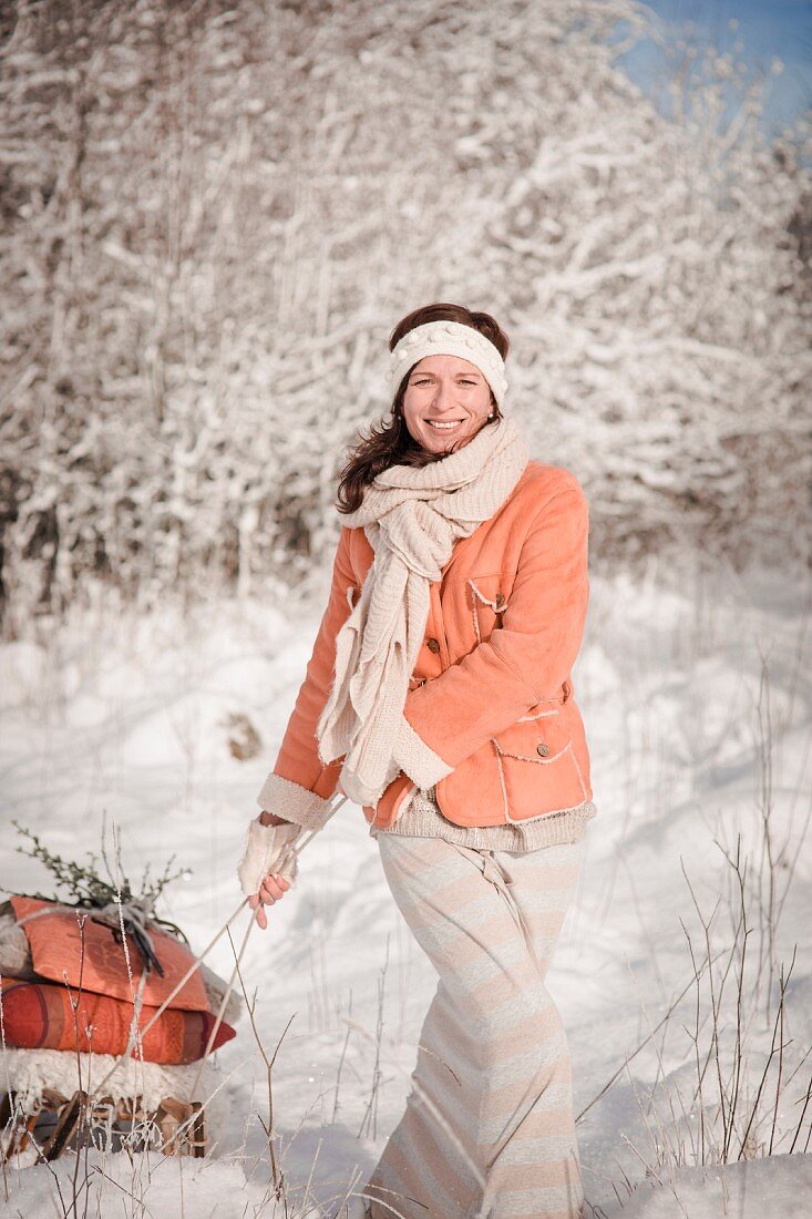 Woman pulling a loaded sledge through a winter landscape
