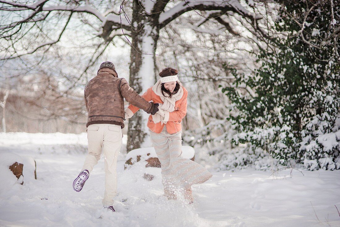 Mann und Frau tanzen in verschneiter Winterlandschaft