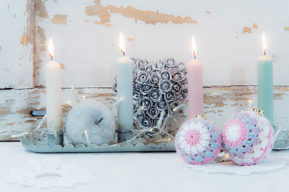Pastel candles on tray and Christmas-tree baubles with crocheted covers
