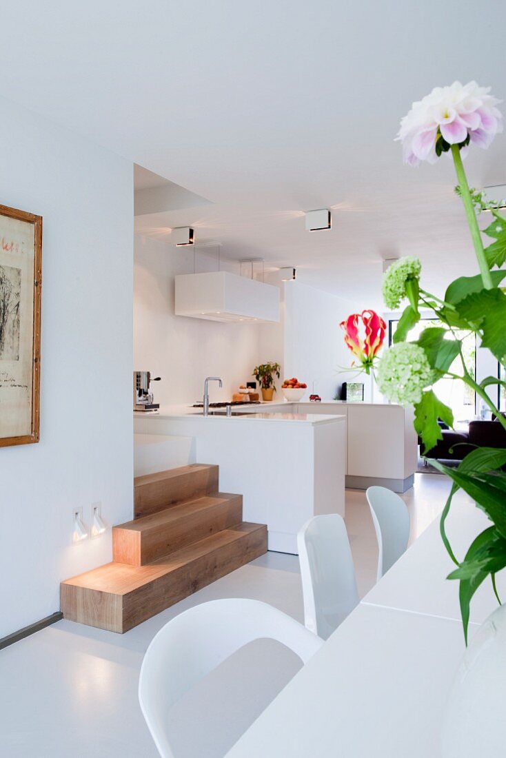 Blick vom Esstisch mit Blumen auf moderne offene Küche