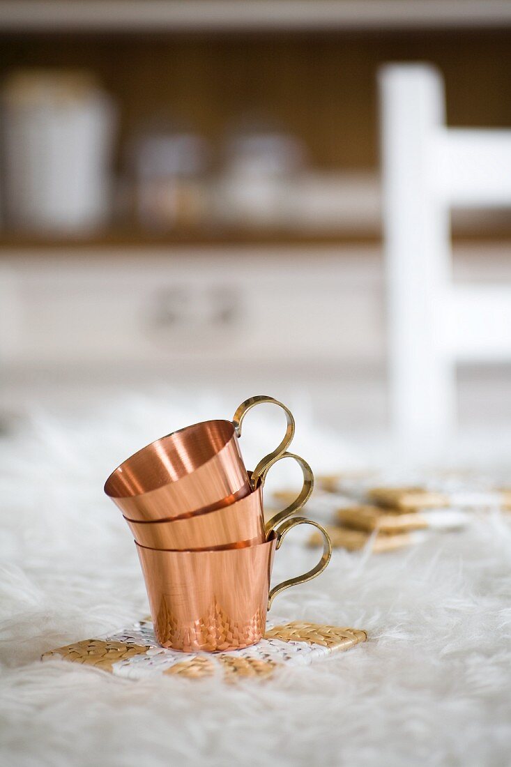 Stacked copper cups on painted seagrass coasters