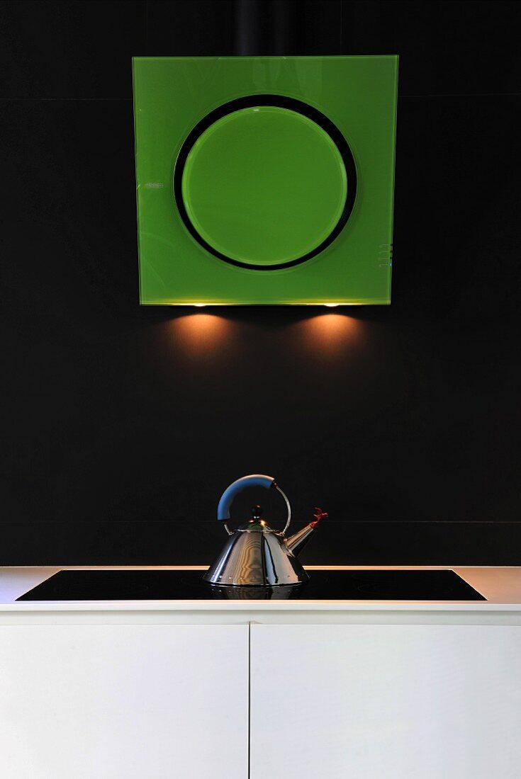 Futuristic, green extractor hood with integrated lighting above kettle on hob