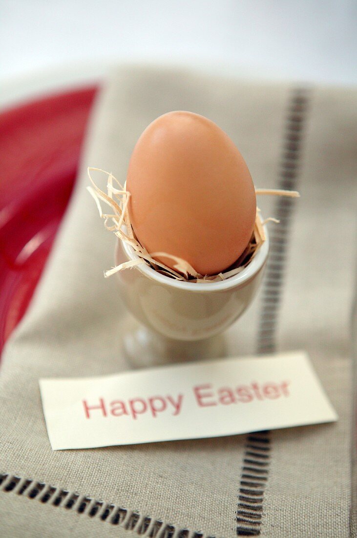 Frühstücksei im Eierbecher dekoriert mit Happy Easter-Schildchen