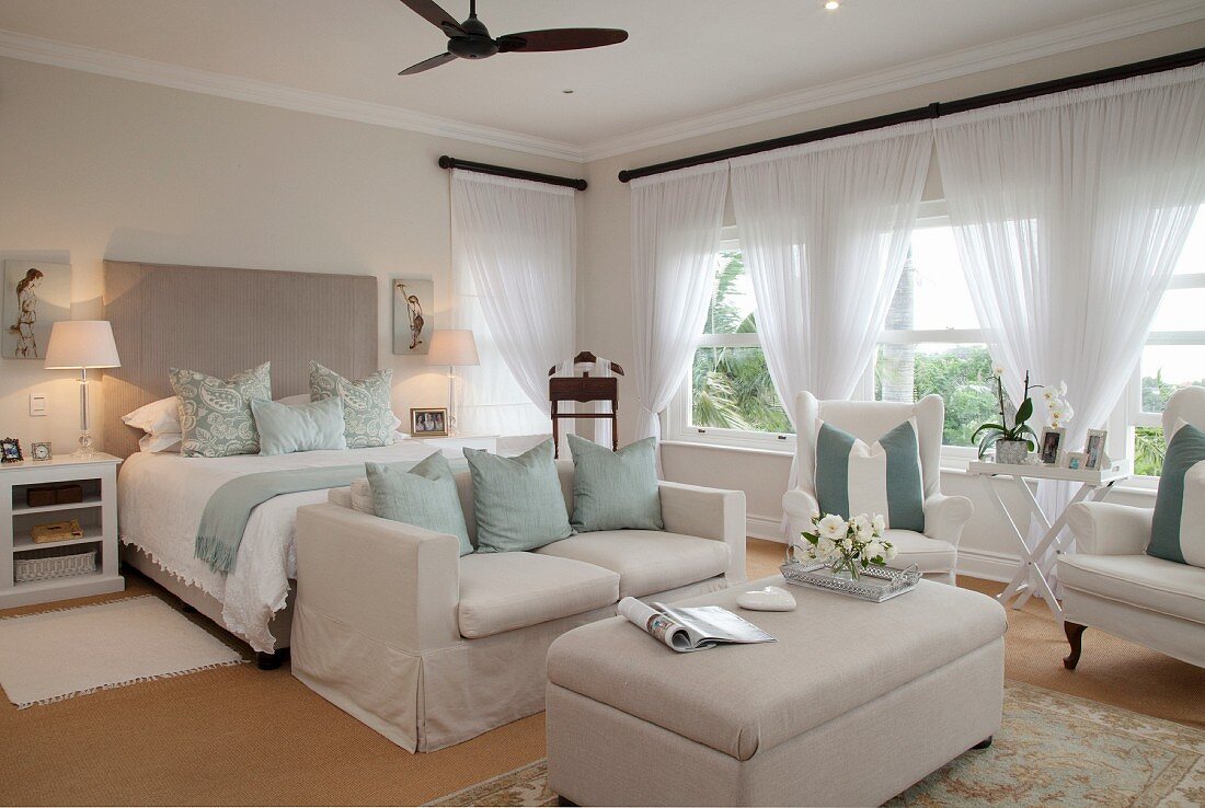 Gemütlicher Loungebereich mit Sofa und Coffeetable vor Doppelbett in grosszügigem Schlafzimmer
