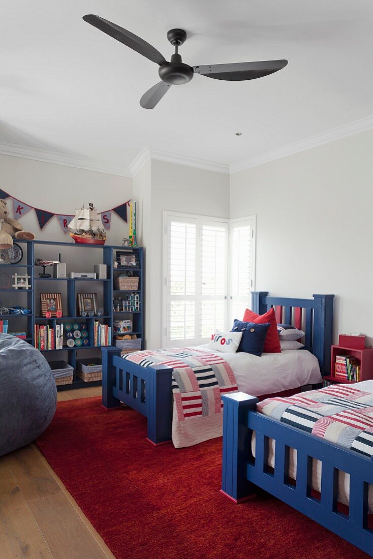 Einzelbetten mit massivem, blau lackiertem Holzgestell, Tagesdecke mit Patchwork Muster, an Decke Ventilator