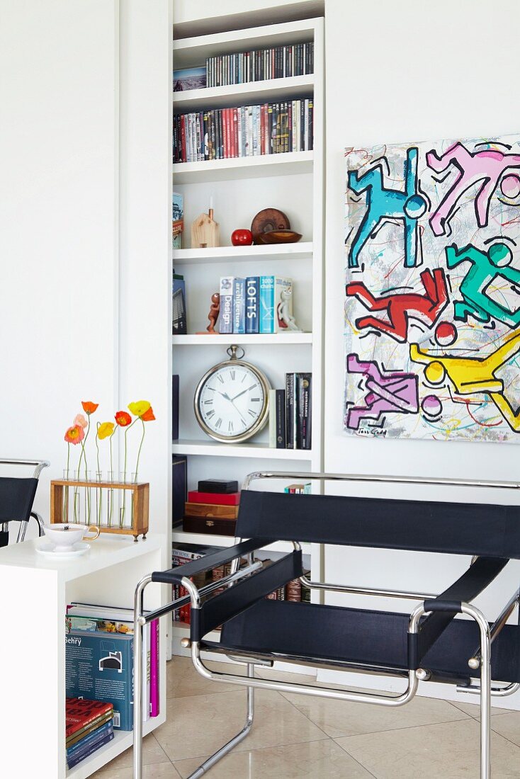 Klassikerstuhl vor Bild im Stile Keith Harings; dahinter eine Regalnische mit Schiebetür als Stauraum