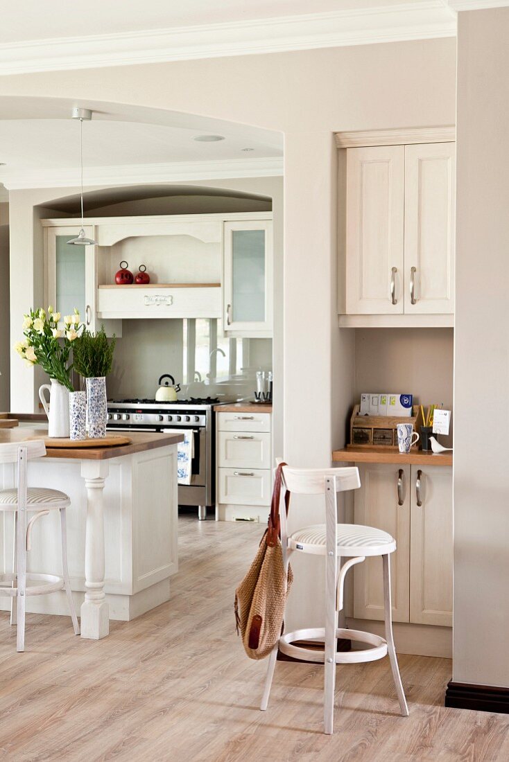 Small workspace integrated in niche next to white, open-plan, country-house kitchen