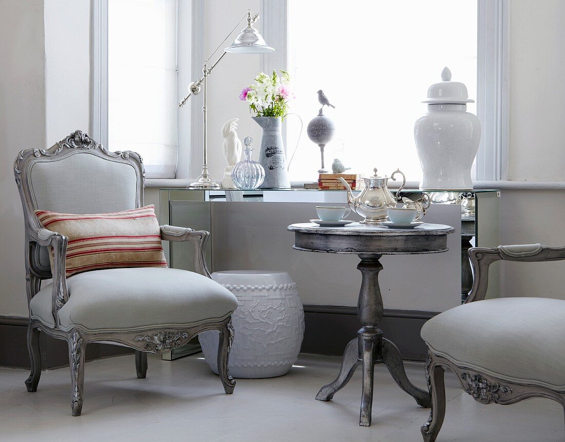 Neoantike Sessel in Grau und passender Beistelltisch mit Teeservice vor Fenster