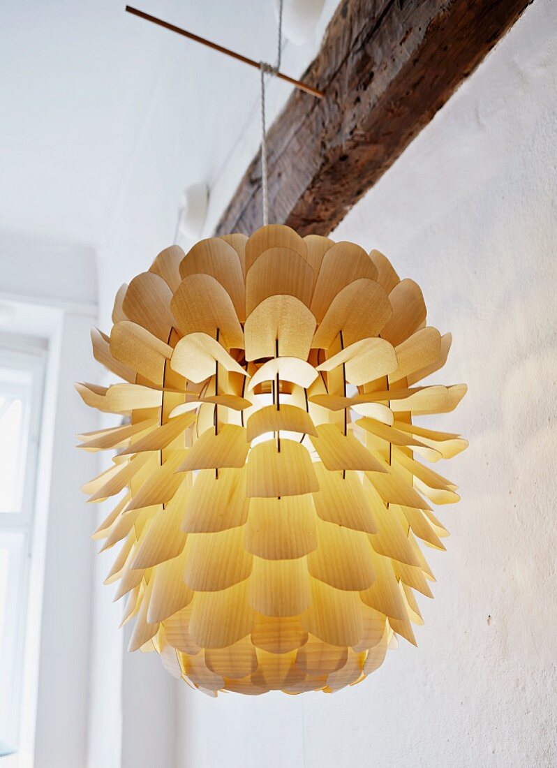 Hand-crafted lampshade made from delicate wooden scales hung from wooden rod