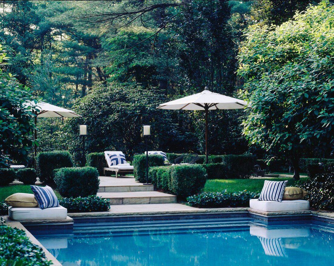 Gartenanlage mit Ruheplätzen unter Sonnenschirmen und Pool