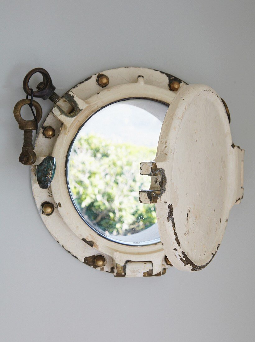 Vintage porthole built into house wall with view into garden