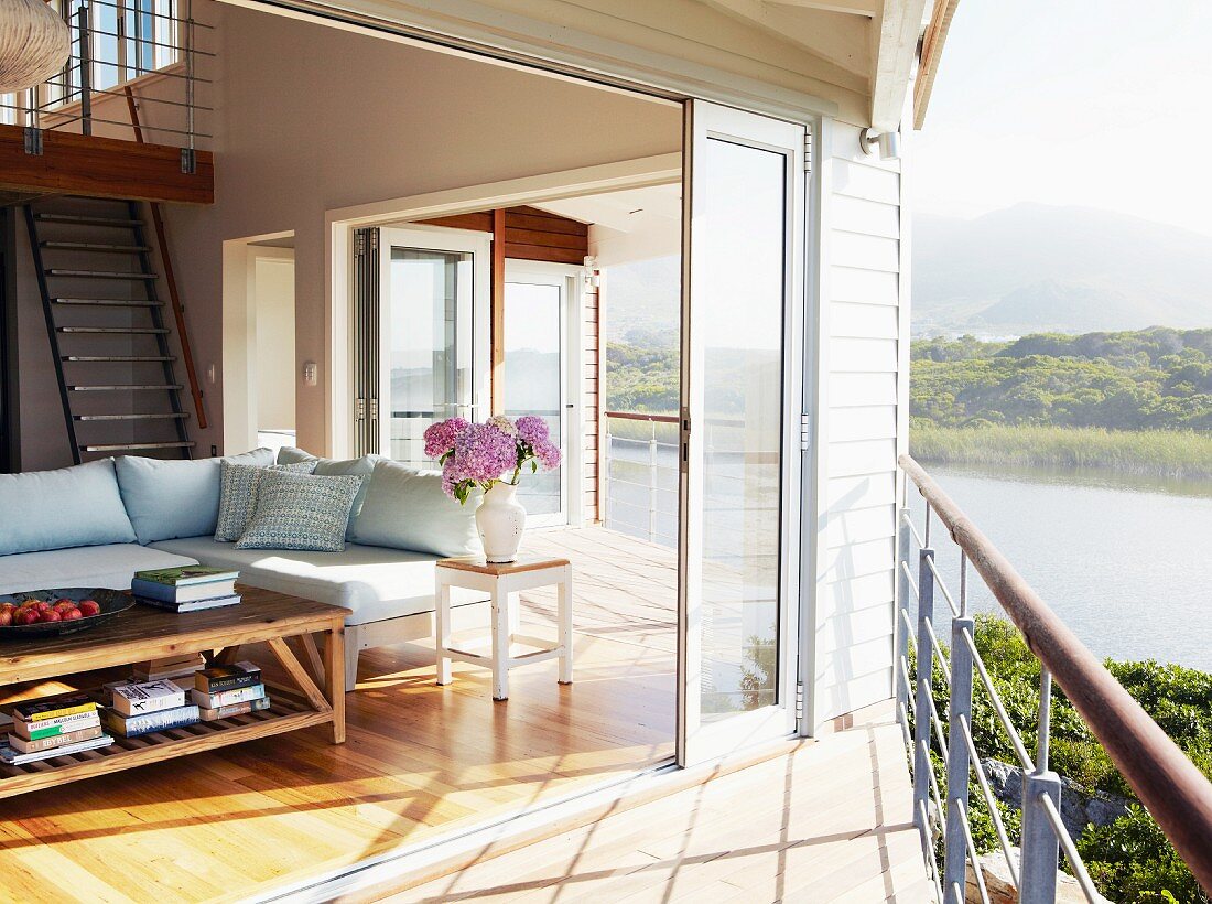 Blick von der Terrasse in offenen Wohnbereich mit Galerietreppe eines Ferienhauses mit Lagunenlandschaft