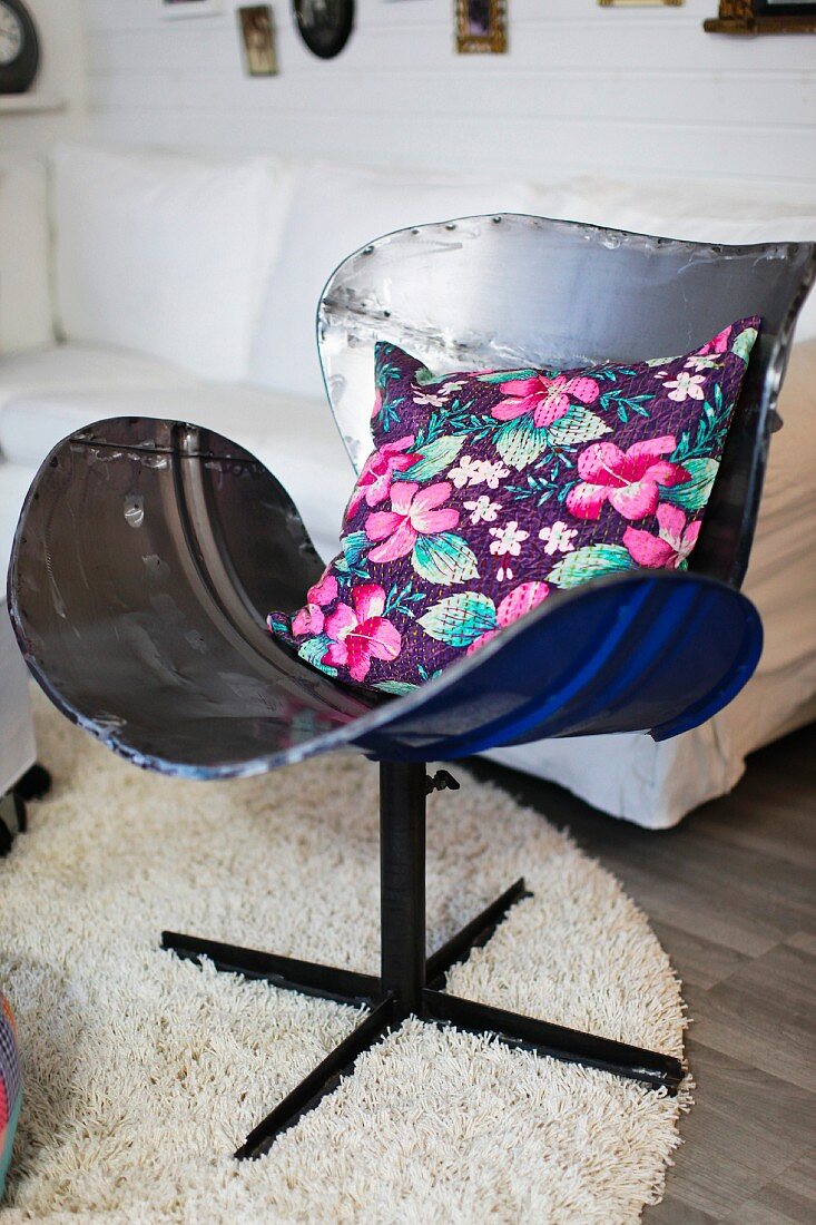 Floral cushion on vintage chair made from recycled metal and long-pile rug