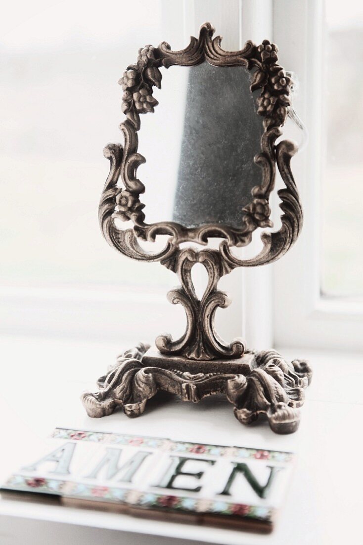 Antique make-up mirror with ornate, silver-coloured frame