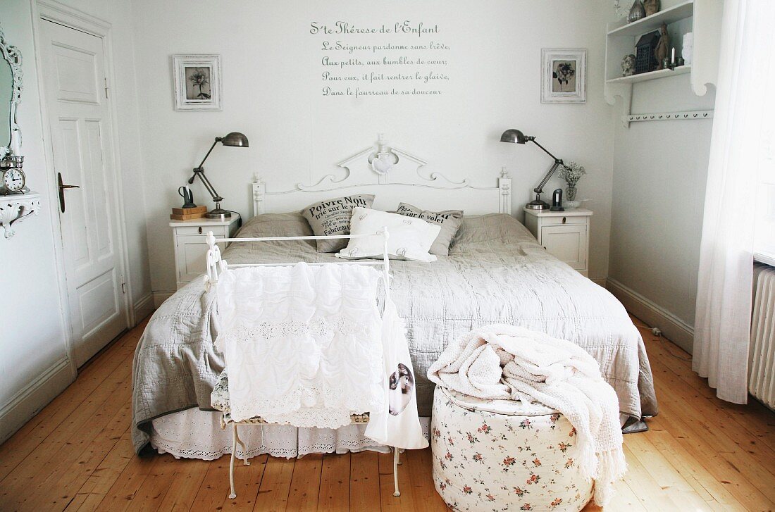 Stummer Diener und Pouf vor Doppelbett, an Kopfende geschnitztes Holzpaneel, weiss lackiert im Elternschlafzimmer