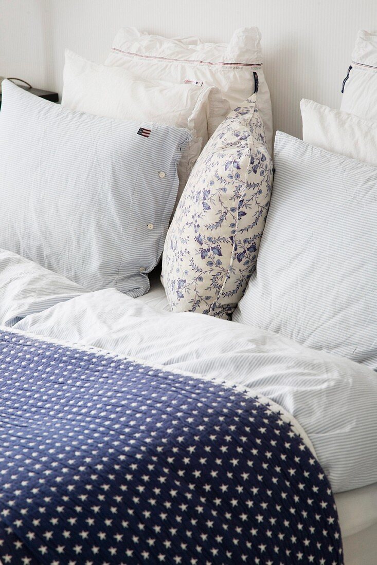 Tagesdecke mit blau weißem Sternenmuster und Kissenstapel auf Bett