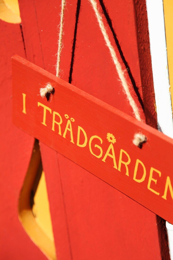 Schwedisch beschriftetes Schild an der rot lackierten Fassade eines Holzhauses