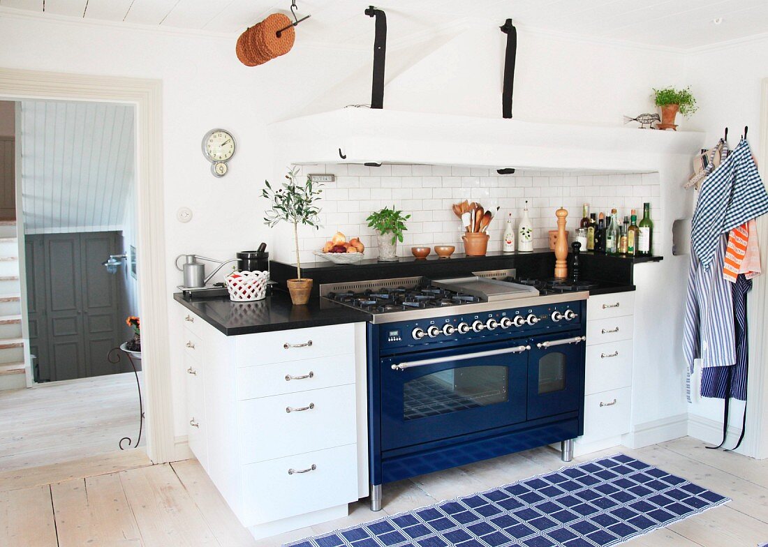 Küchenzeile mit blauem Retro-Herd und integriertem Dunstabzug, davor ein blaukarierter Teppich