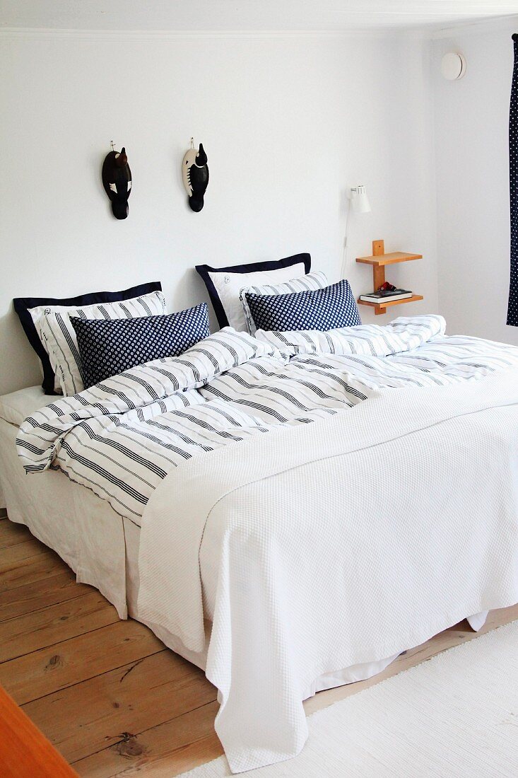 Double bed with Scandinavian-style, blue and white covers below wooden ducks on wall