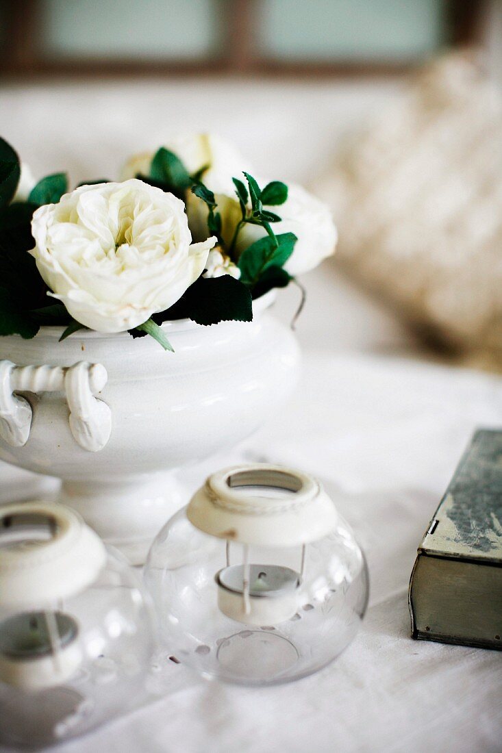 Windlichter und weiße Rosen in Porzellanvase