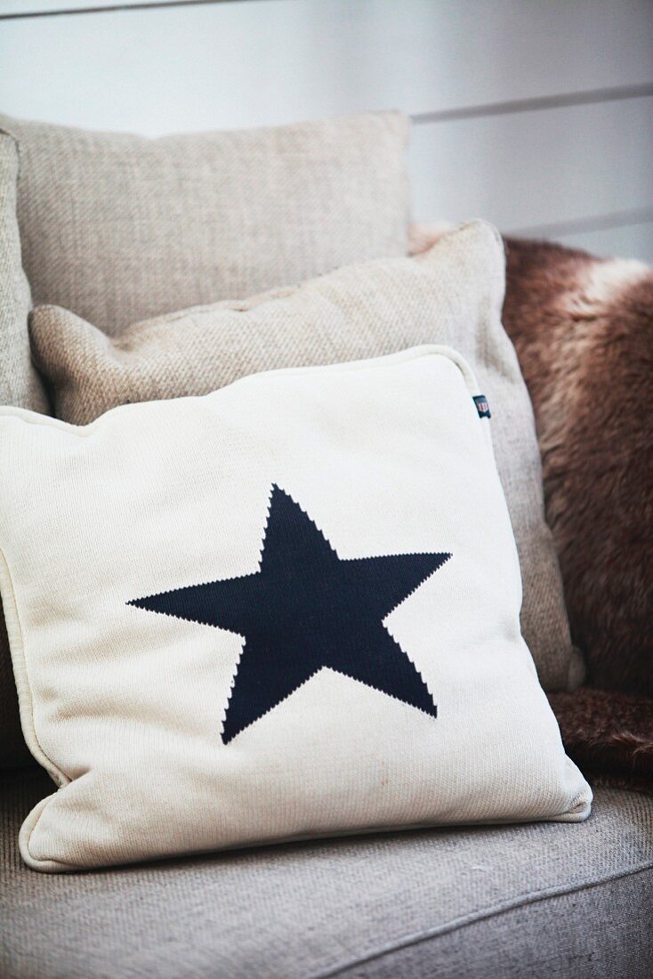 Pale scatter cushion with black star motif on sofa