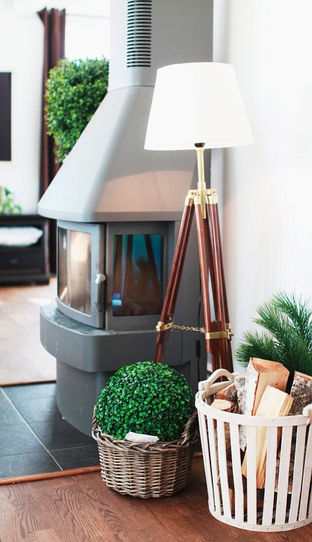 Standard lamp with maritime, tripod base and basket of firewood next to wood-burning stove