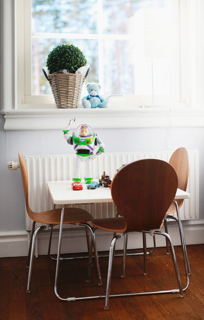 Children's table and engineered wood chairs with steel tube frames below window
