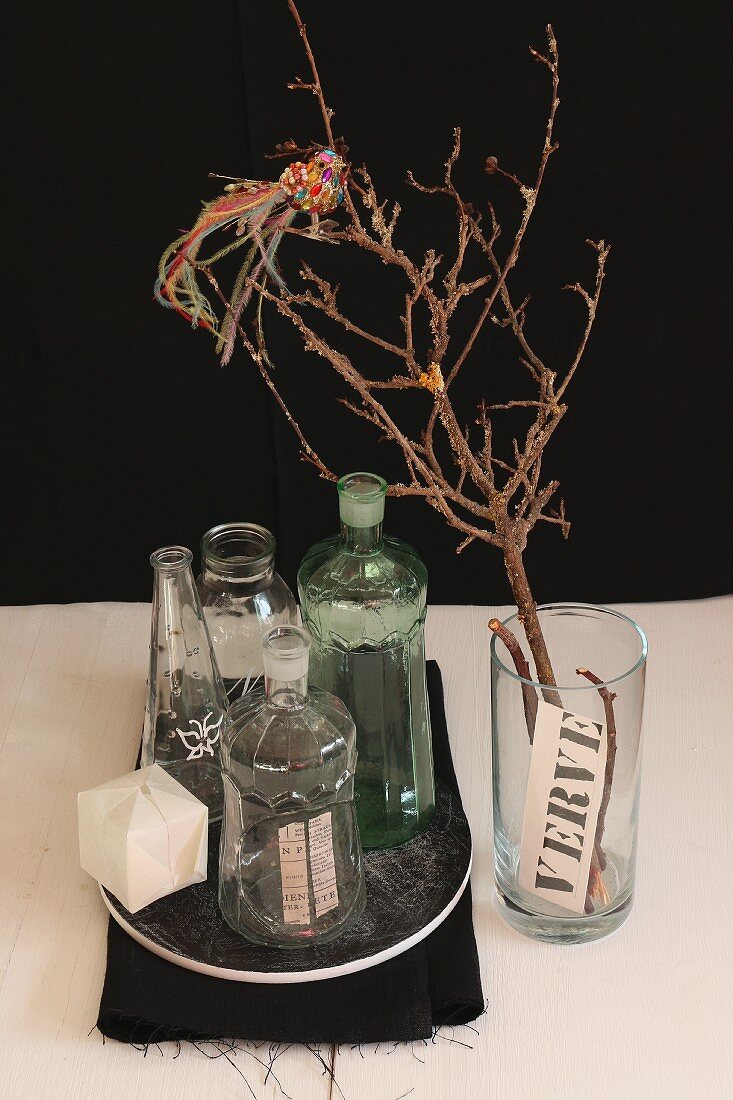 Dekorative Vintage-Glasväschen; daneben ein Glas mit einem trockenem Zweig und darauf sitzendem Glasvogel