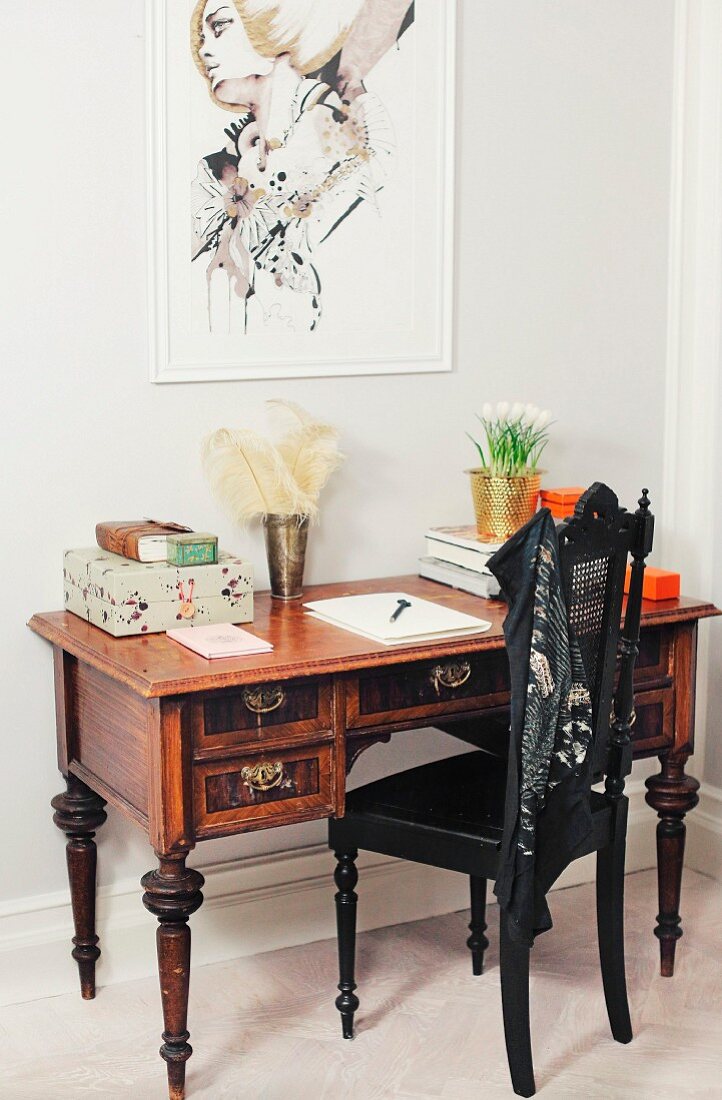 Wilhelmine-era chair painted black at Biedermeier-style writing desk below modern portrait on wall