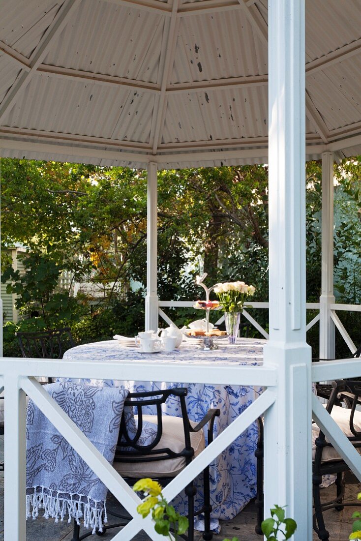 Runder Tisch mit Decke und Gartenstühle in Gartenpavillon