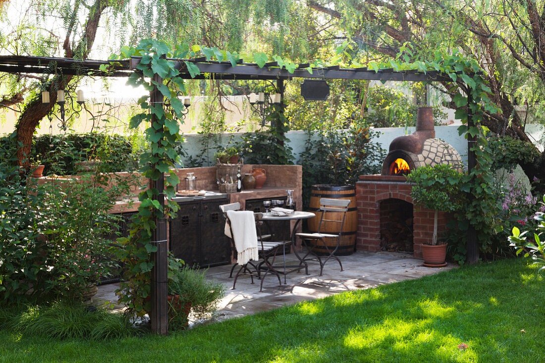 Pergolaterrasse mit Aussenküche, Sitzplatz und gemauertem Pizzaofen in gepflegtem Garten