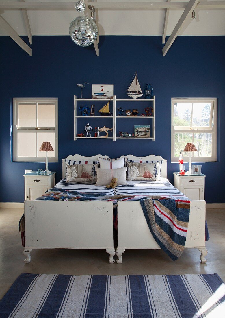 Twin beds against wall painted dark blue in bedroom with maritime ambiance