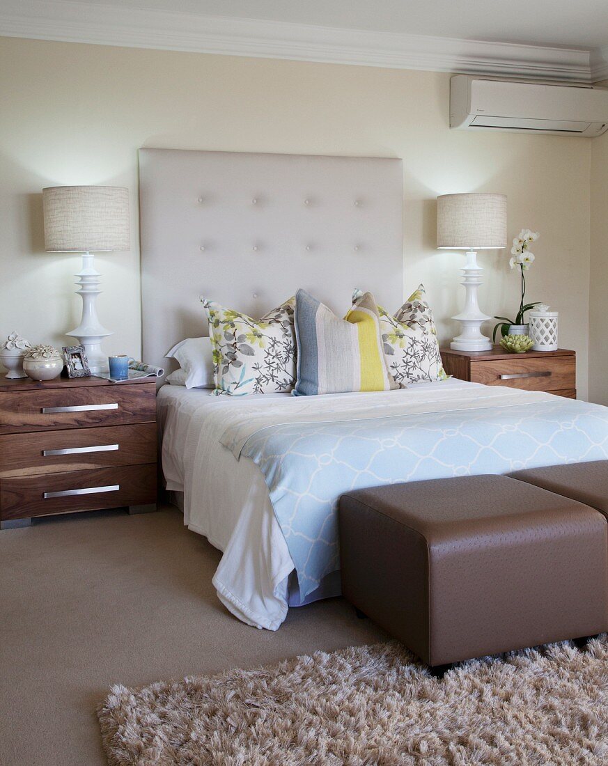 Elegantes Schlafzimmer in gedeckten Farben, gepolstertes Betthaupt und symmetrische Nachtkästchen