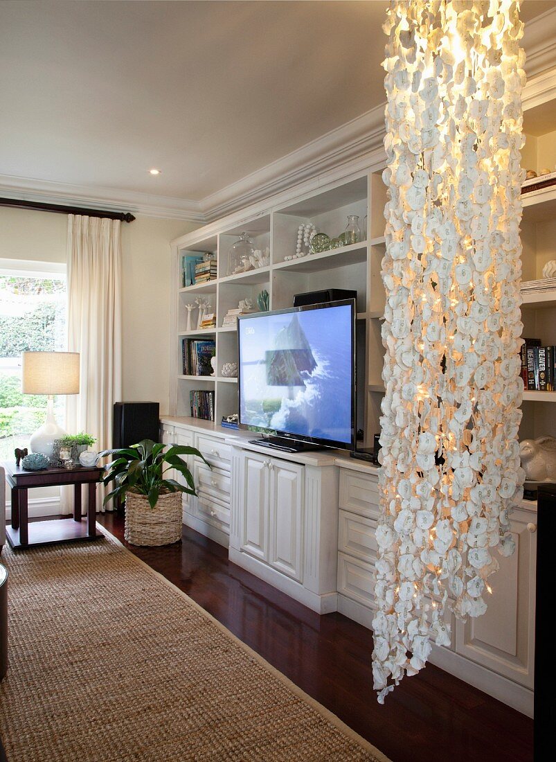 Classic fitted cabinets with large flatscreen TV and ceiling-to-floor capiz-shell lamp in foreground