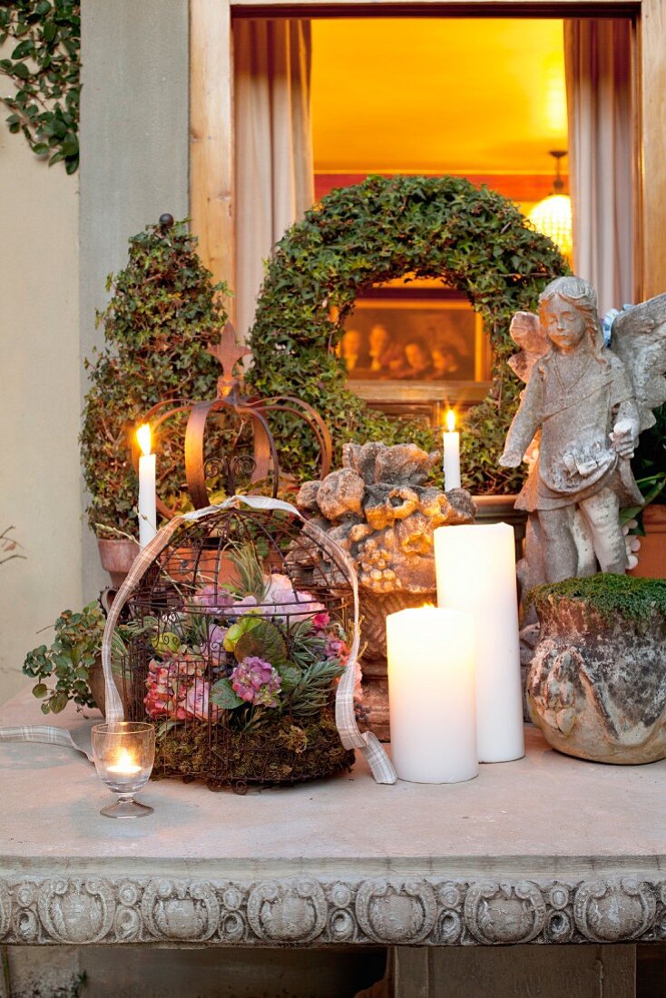Weihnachtlich dekorierter Terrassentisch mit Blumengesteck in Drahtkorb und brennende Kerzen