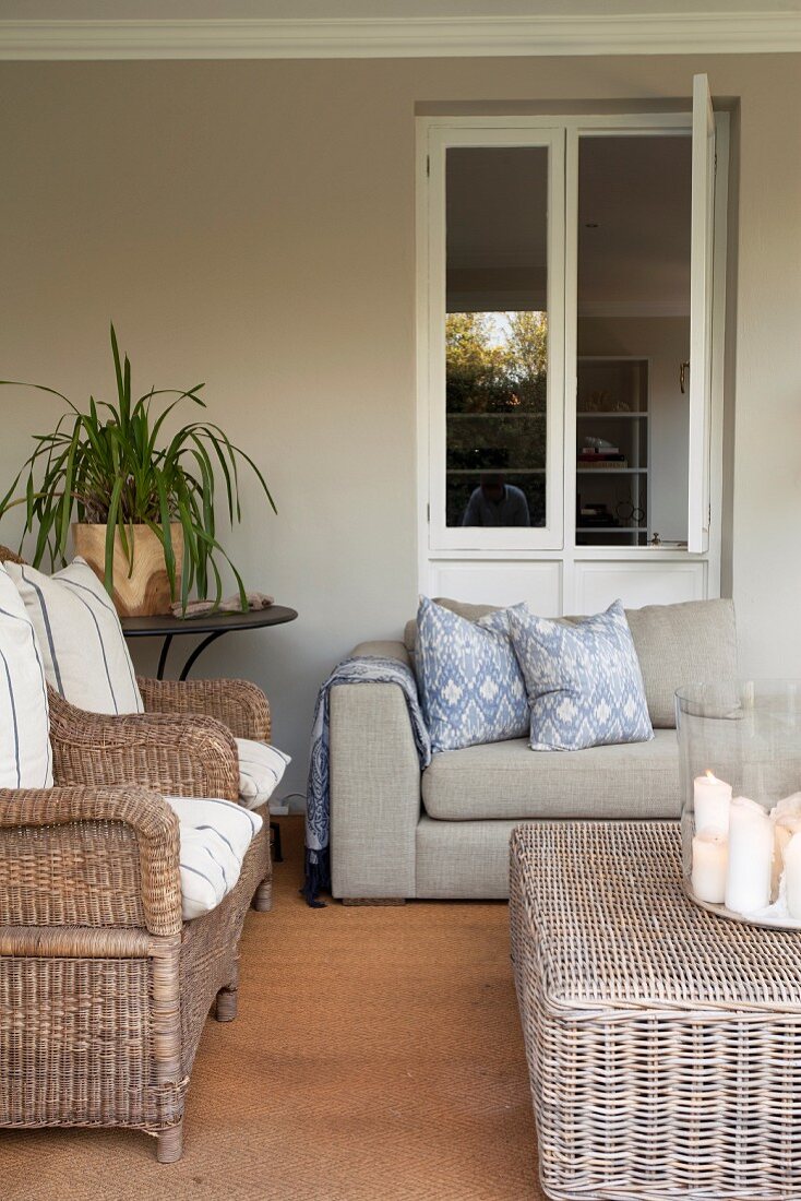 Loggia with wicker armchairs and modern sofa below open window