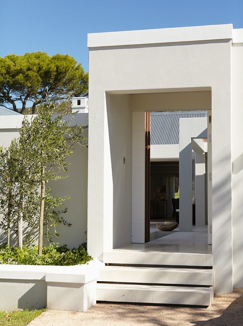 Steps leading to open, white entrance in wall with view into courtyard