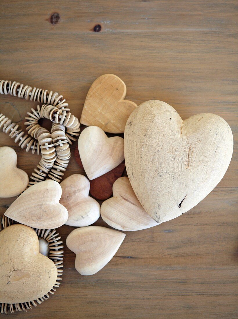 Verschieden grosse Herzen und Perlenkette aus Holz auf Ablage