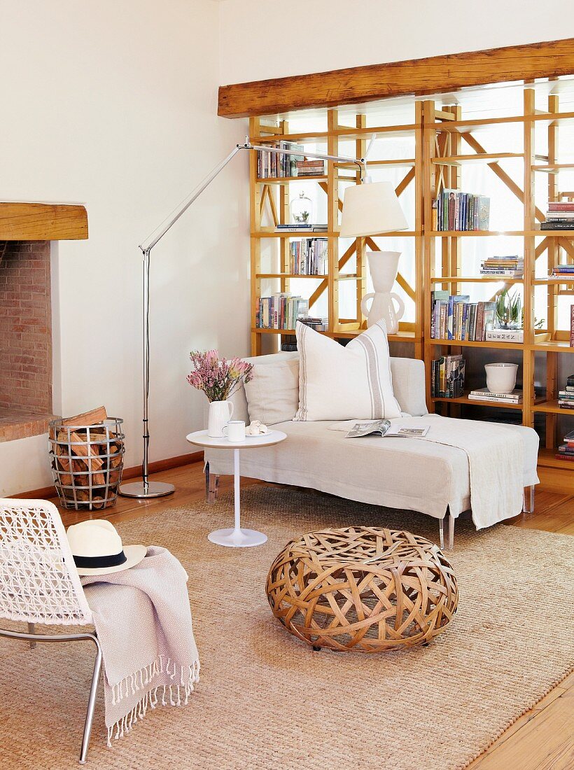 Wicker pouffe and chaise longue in front of wooden partition shelving
