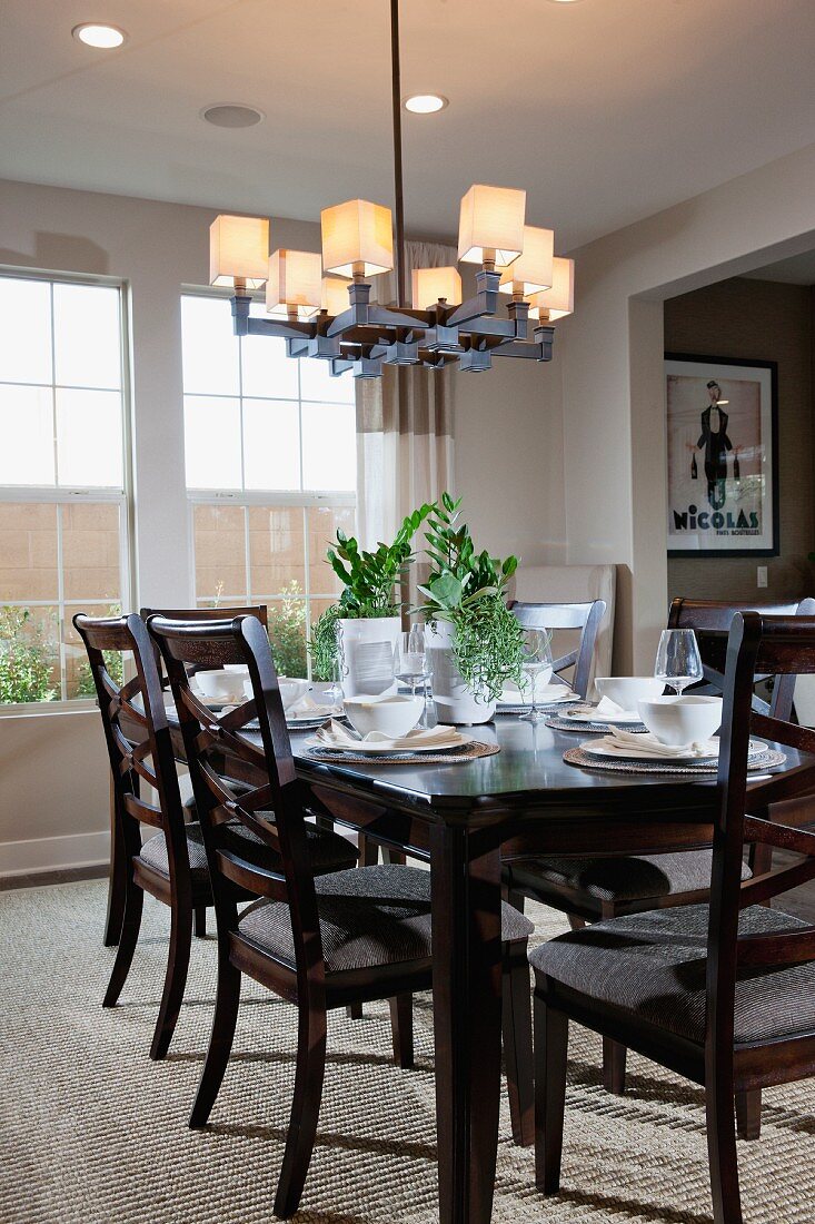 Wooden chairs around dining table below chandelier; Irvine; California; USA