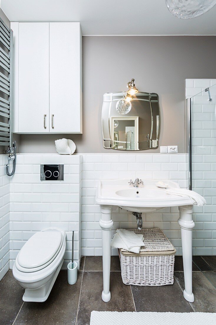 Washstand with white, turned legs against half-height tiling on wall and grey floor tiles