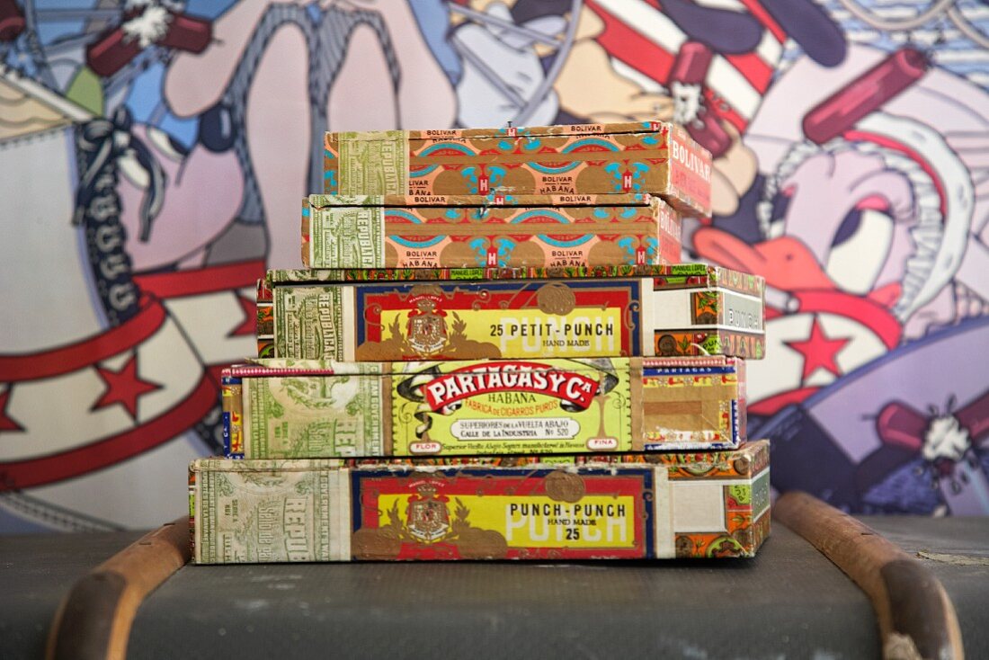 Zigarrenkistchen auf altem Koffer gestapelt vor Hintergrund im Comicstil