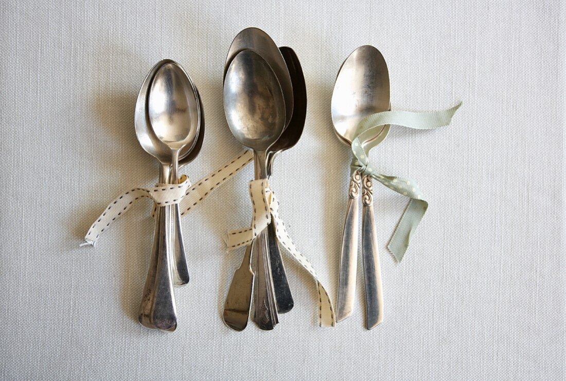 Various silver spoons tied together with ribbon