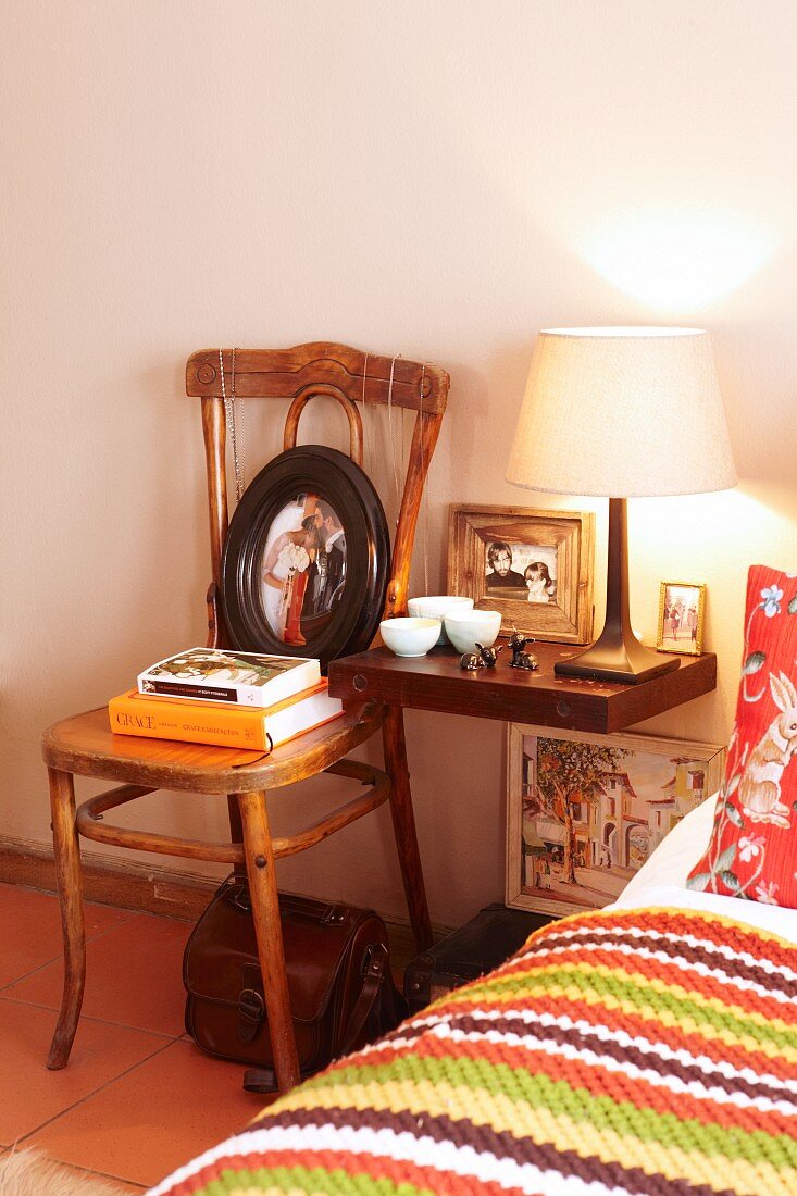 Mit Flohmarktartikeln und Bildern dekorierter Nachttisch neben gemütlichem Mustermix auf Bett im Schlafzimmer