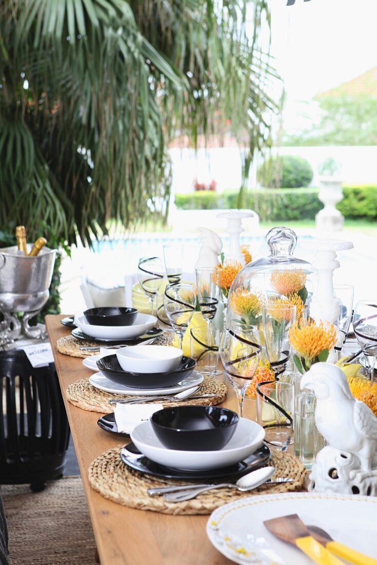 Festlich gedeckter Tisch auf Terrasse mit exotischer Blumendeko & Porzellanpapageien