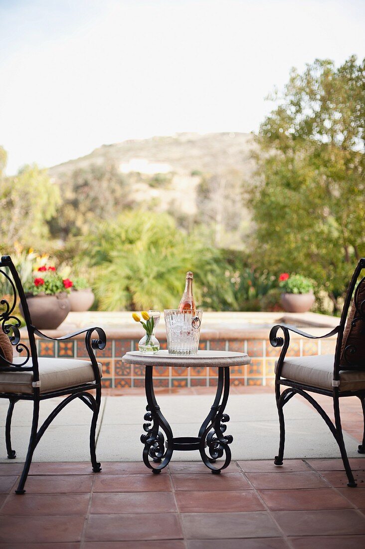 Terrassenstühle & Tischchen auf mediterraner Terrasse mit Blick auf Wasserbecken