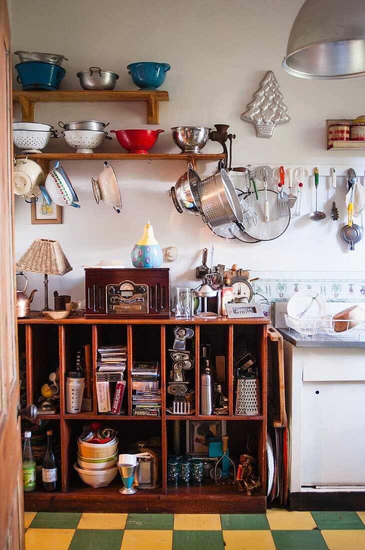 Vintage-Küche mit hängender und aufgestellter Küchensiebsammlung und offenem vollgestelltem Holz-Küchenregal