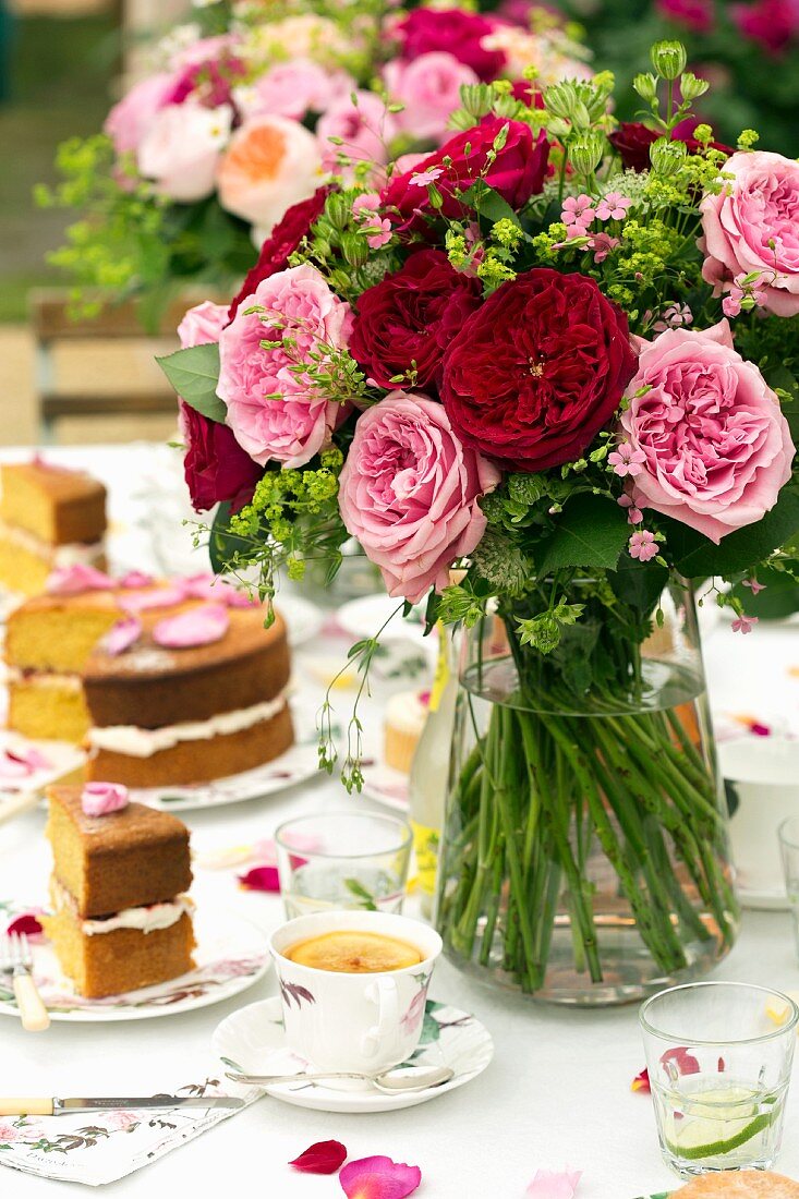 Sommerblumensträusse auf gedecktem Kaffeetisch mit Torte und Kaffeetassen